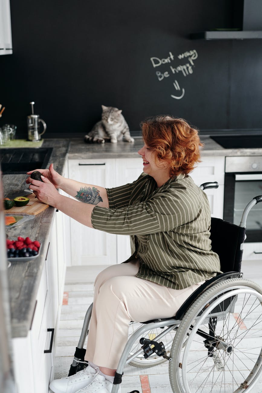 woman sitting on wheelchair while holding avocado