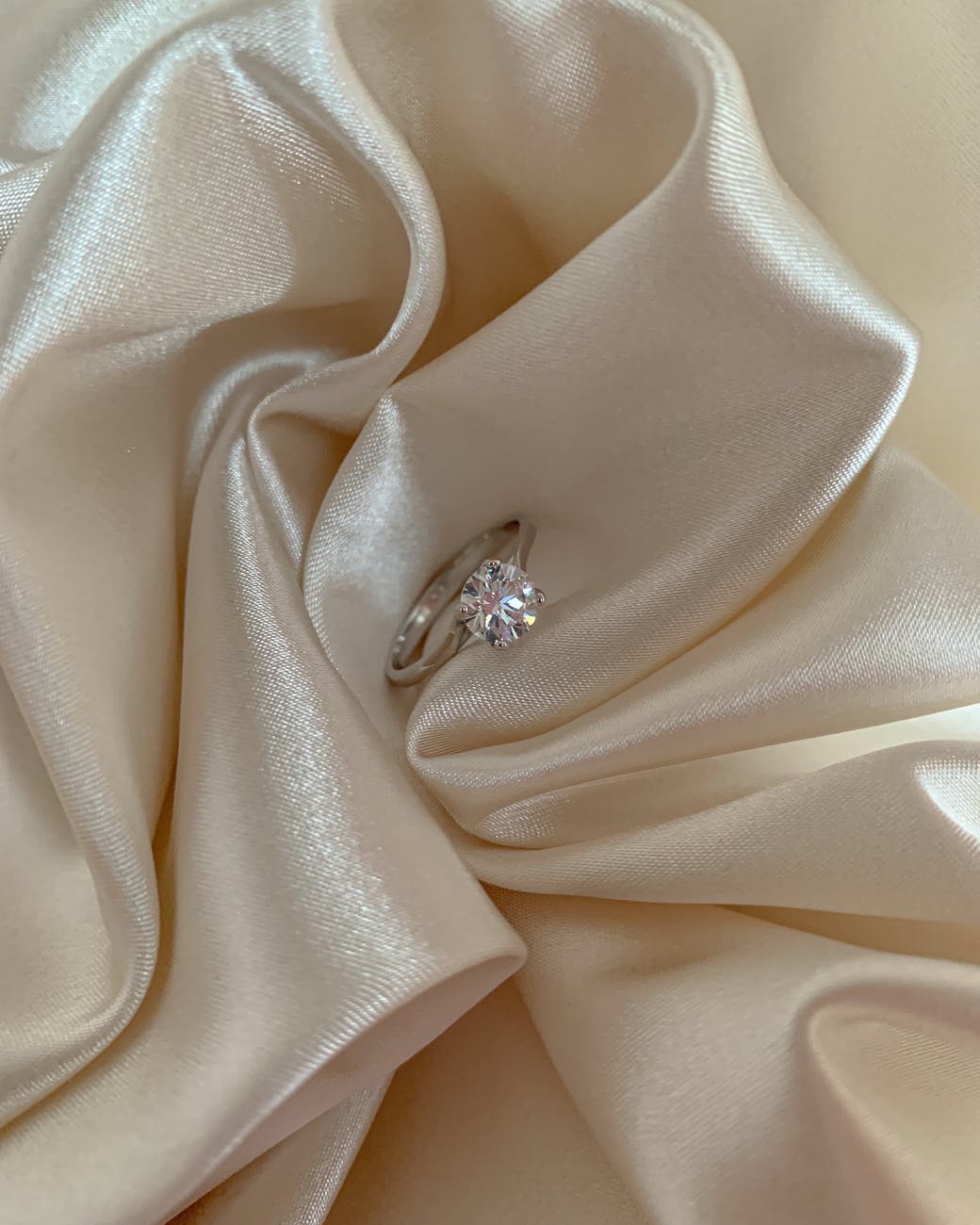 silver diamond ring on white textile