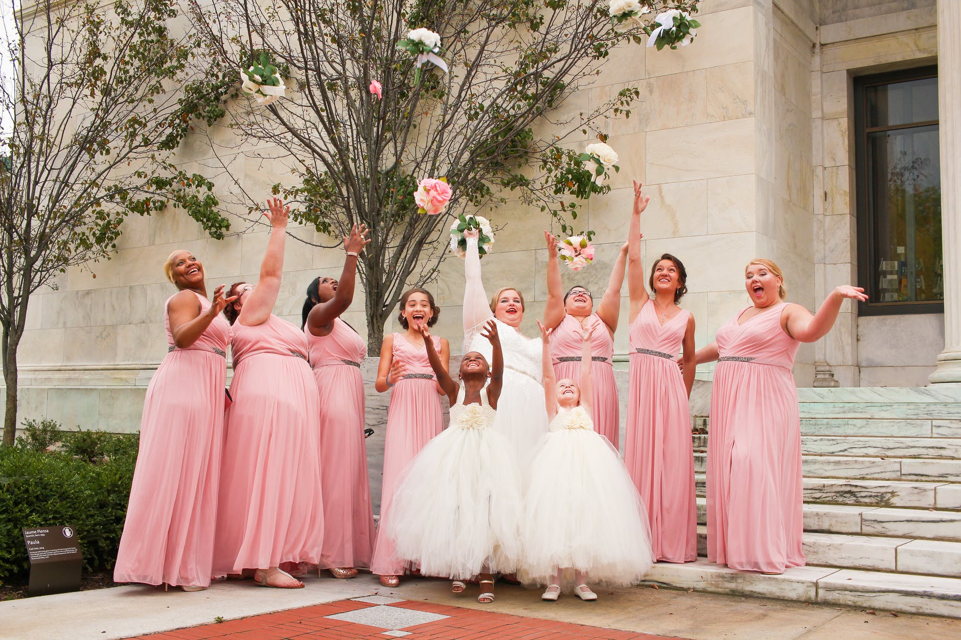 women wearing dresses while throwing bouquets