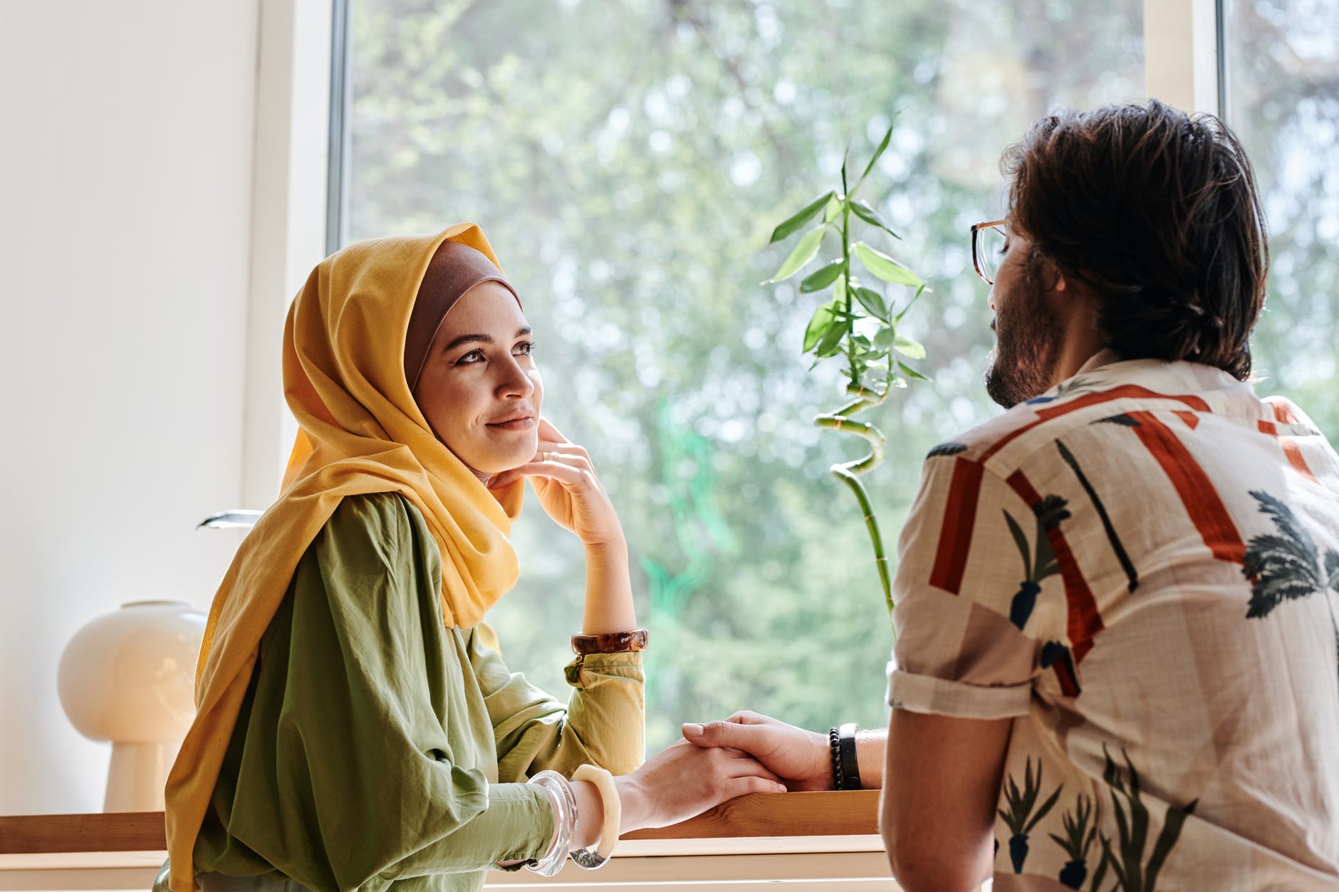 woman in yellow hijab sitting a bearded man