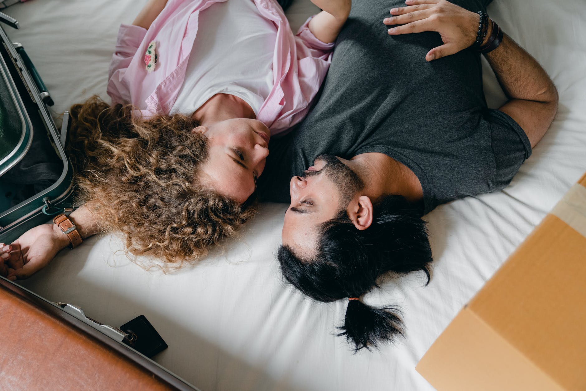 diverse couple lying on bed at home